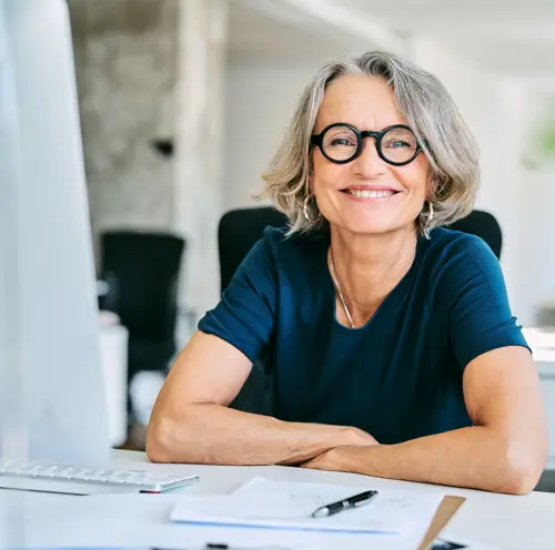 smilende dame ved arbeidspulten sin